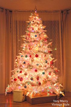 a white christmas tree with colorful lights and ornaments in the shape of an xmas tree