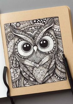 an owl is drawn on top of a notebook with a black marker and some pens