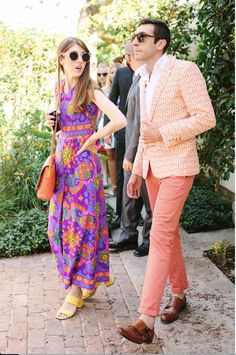 a man and woman walking down a sidewalk next to each other wearing bright colored clothing