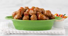 a green bowl filled with meatballs on top of a table