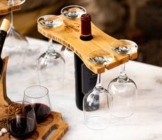 several wine glasses are sitting on a wooden tray next to a bottle and glass holder