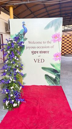 a welcome sign with flowers on the red carpet