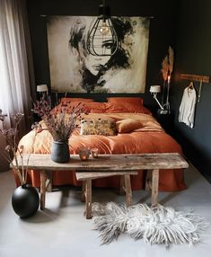 a bedroom with an orange bed spread and white fur rugs on the floor next to a wooden bench