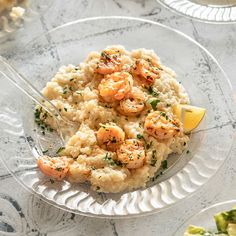 shrimp and grits on a clear plate with lemon wedges