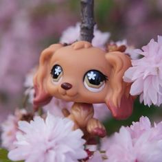 a little dog figurine sitting on top of a tree filled with pink flowers