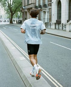 a man running down the street wearing a training club shirt