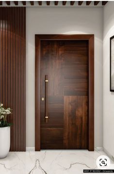 a wooden door in a white room next to a vase with flowers on the floor