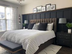 a bedroom with black and white bedding, gray headboard, and two framed pictures on the wall