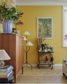 a living room with yellow walls and wooden flooring is pictured in this image, there are two lamps on either side of the table