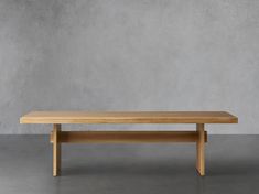 a wooden table sitting on top of a cement floor in front of a concrete wall