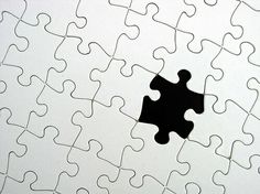 a black piece of puzzle sitting on top of a white wall