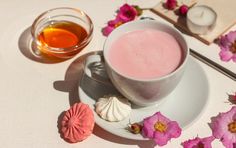 a cup of tea next to some pink flowers and other items on a table top