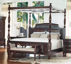 a bedroom with hardwood floors and white walls, including a four poster bed in the center