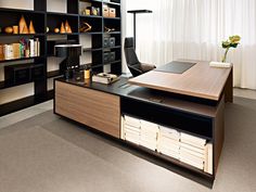 an office with black and wood furniture, bookshelves and shelves filled with papers