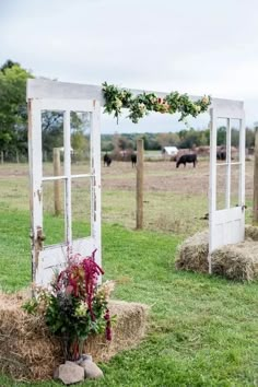 an old door is decorated with flowers and greenery in the middle of a field