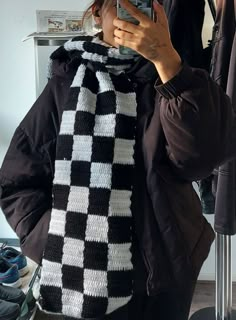 a woman taking a selfie in front of a mirror wearing a black and white scarf