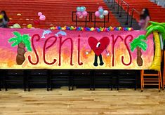 a banner with the word seniors on it in front of some chairs and palm trees