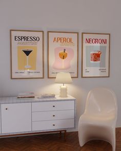 a white chair sitting next to a table with a lamp on it in front of two posters