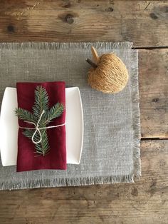 a place setting with red napkins, pine cone and twine on the table