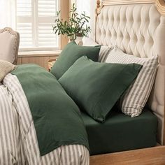 a bed with green sheets and pillows in a bedroom