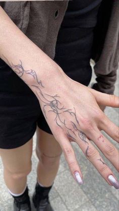 a woman's hand with tattoos on it and her fingers in the shape of hands