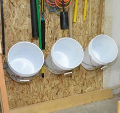 three white urinals mounted to the side of a wall in a construction area