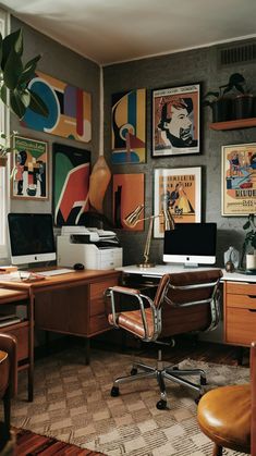 a home office with lots of art on the wall and desks in front of it