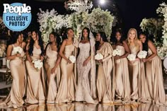 a group of women standing next to each other in front of a white flower covered wall