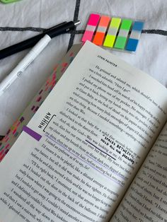 an open book sitting on top of a table next to markers and pens, scissors