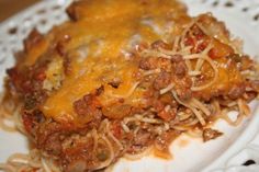 a white plate topped with lasagna covered in meat and cheese on top of it