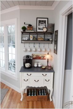 a kitchen with white cabinets and shelves filled with bottles on top of wooden flooring