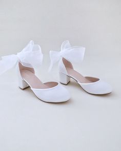 a pair of white shoes with bows on them