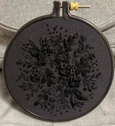 a black embroidery on a gray jacket with flowers