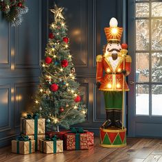 a large nutcracker standing next to a christmas tree