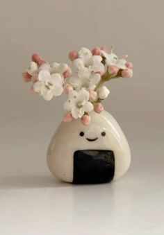 a white vase with pink and white flowers in it's mouth, sitting on a table