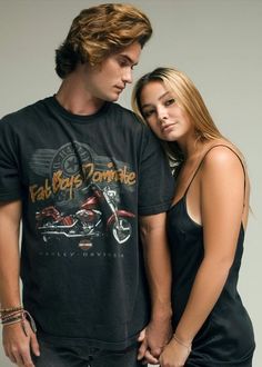 a man and woman standing next to each other in front of a gray background wearing black clothing