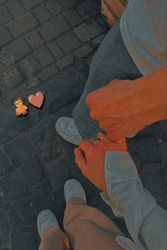 two people standing next to each other on a brick road with one person holding a small teddy bear