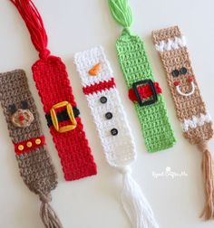 four crocheted christmas bookmarks with tassels on them, all decorated in different colors