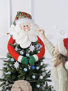 a girl decorating a christmas tree with santa clause