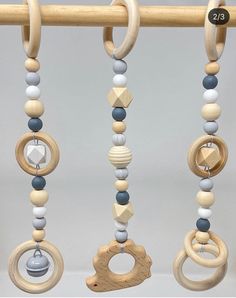 three wooden toys are hanging from a rod with beads and rings on it's sides