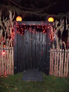 a wooden gate decorated with lights and pumpkins