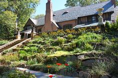 the house is surrounded by beautiful flowers and greenery, with stairs leading up to it