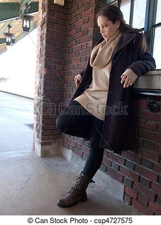 a woman sitting on a window sill in front of a brick wall and looking out the window