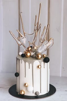 a white cake with gold decorations on top and icing drizzled around it