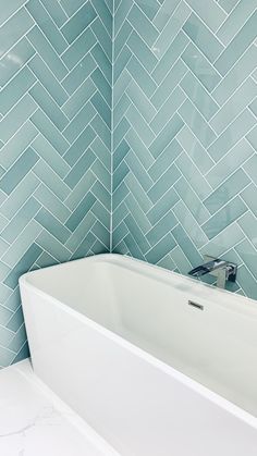 a white bath tub sitting next to a tiled wall