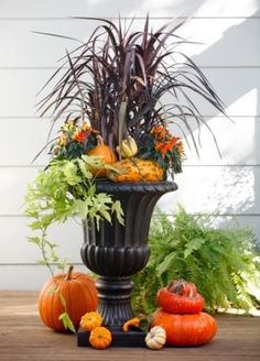 a tall planter filled with lots of different types of flowers and plants sitting on top of a wooden table