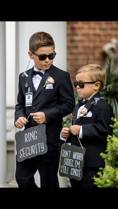 two young boys dressed in black suits and sunglasses, one holding a sign that says ring security