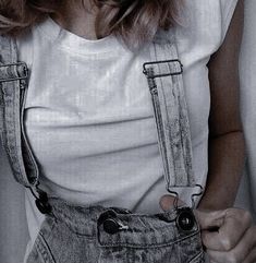 a woman wearing overalls and a white t - shirt