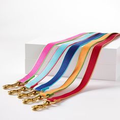 four different colored ribbons with gold handles on white box, one is empty and the other two are closed