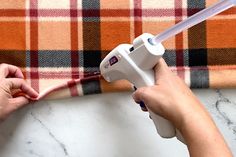 a person using a hair dryer on top of a plaid blanket